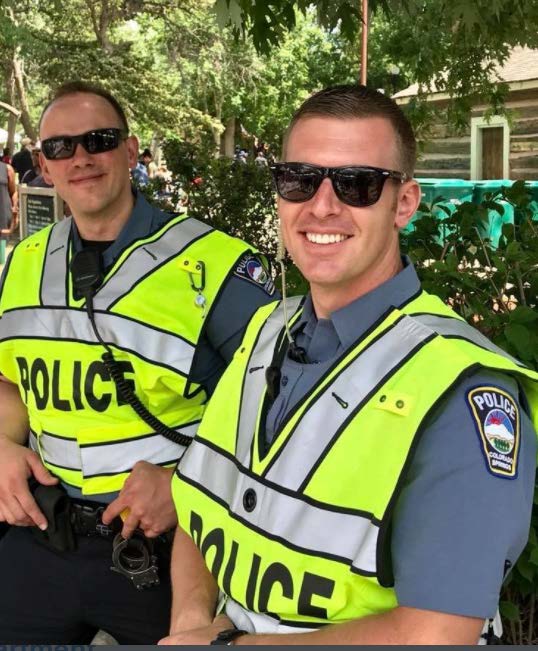 Two white CSPD police offers in neon yellow vests smiling